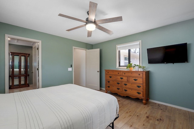 bedroom featuring light wood-style flooring, a ceiling fan, and baseboards