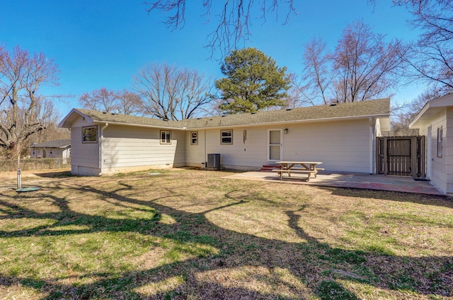 rear view of property featuring a yard, a patio, fence, and a gate