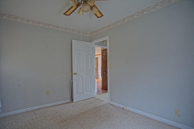 spare room with a ceiling fan, baseboards, and light carpet