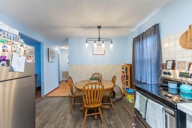 dining room with tile walls, dark wood-style floors, visible vents, and a textured ceiling