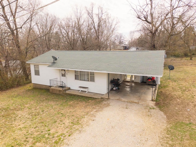 ranch-style home featuring a front yard, a carport, driveway, and roof with shingles