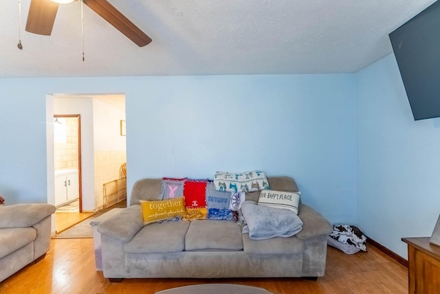 living room with ceiling fan, wood finished floors, and a textured ceiling