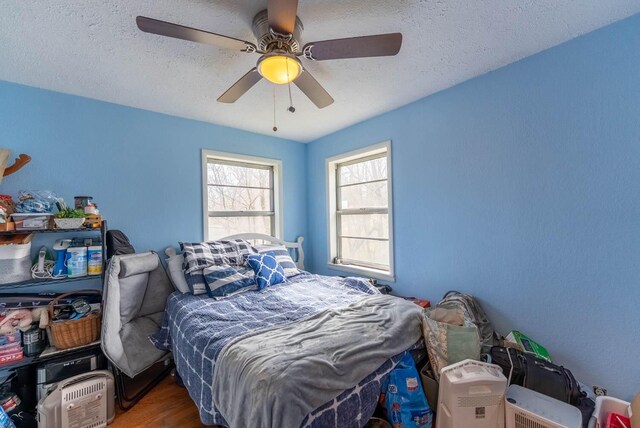 bedroom featuring a textured ceiling, wood finished floors, and a ceiling fan