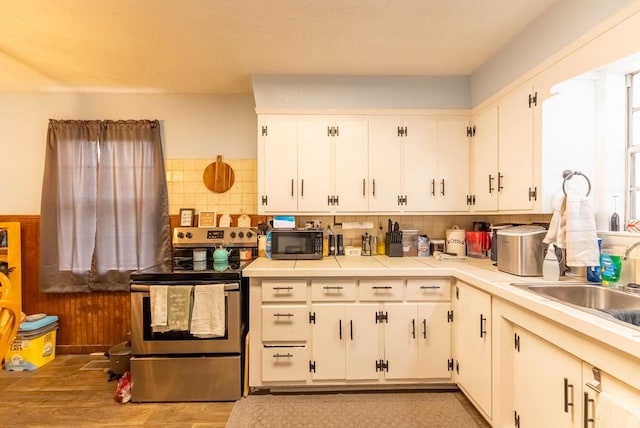 kitchen featuring backsplash, stainless steel electric range, white cabinetry, and black microwave