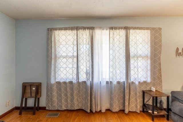 sitting room with light wood-style flooring, baseboards, and visible vents