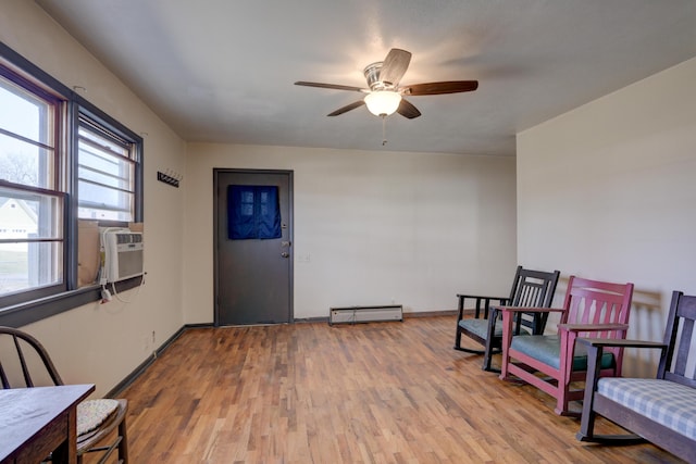 sitting room featuring cooling unit, wood finished floors, baseboards, a ceiling fan, and a baseboard heating unit