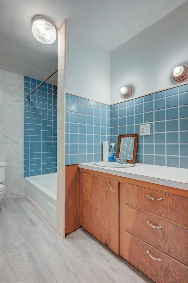 full bath featuring tile walls, shower / washtub combination, toilet, and vanity