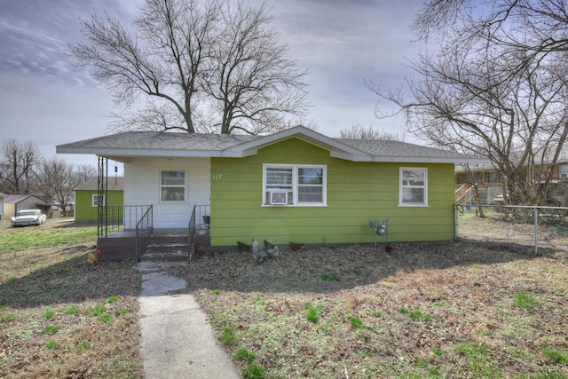 bungalow with a shingled roof and fence