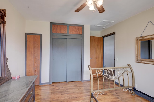 interior space featuring attic access, light wood-style flooring, and ceiling fan