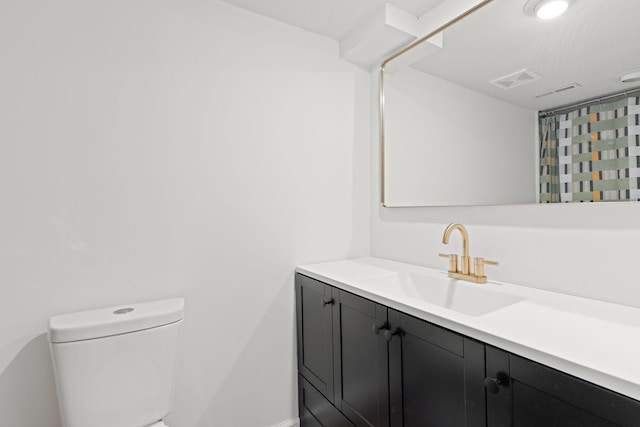 bathroom with vanity, toilet, baseboards, and visible vents