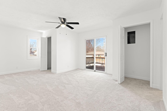 unfurnished bedroom featuring baseboards, light colored carpet, a textured ceiling, a ceiling fan, and access to outside