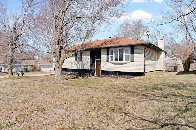 view of front facade with a chimney, a front yard, and fence