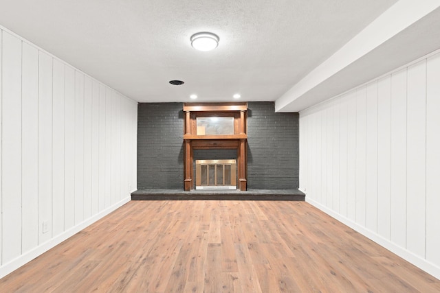 interior space featuring a fireplace, wood finished floors, baseboards, and a textured ceiling