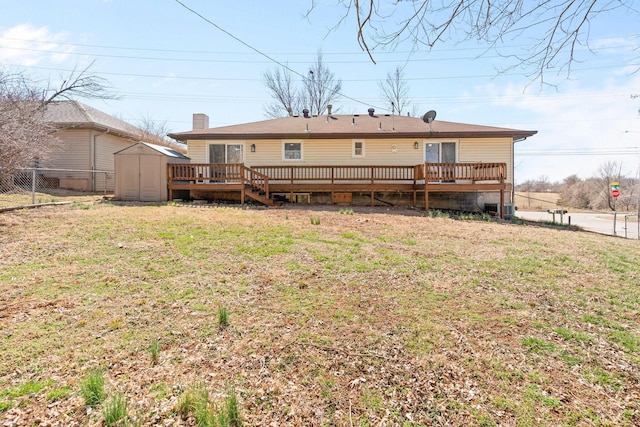 rear view of house with an outbuilding, fence, a shed, a yard, and a deck