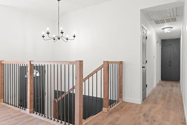 corridor featuring an inviting chandelier, wood finished floors, an upstairs landing, and baseboards