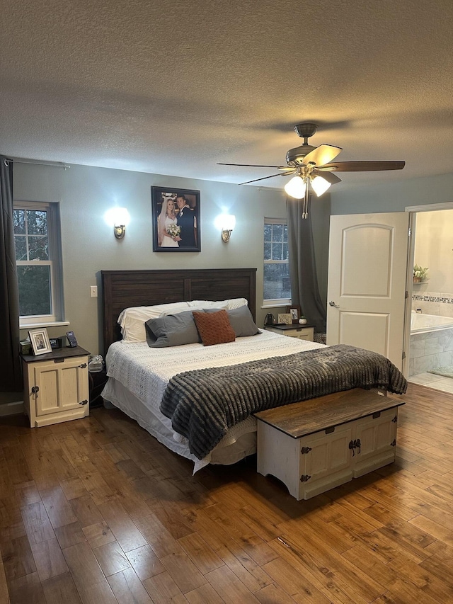 bedroom with dark wood-type flooring, a ceiling fan, and a textured ceiling