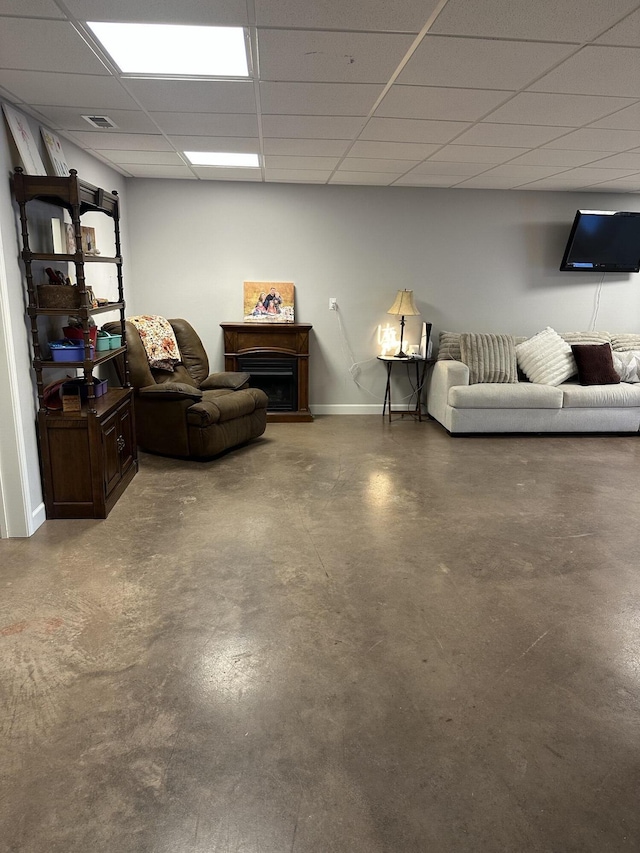 living area with visible vents, finished concrete flooring, baseboards, a fireplace, and a paneled ceiling