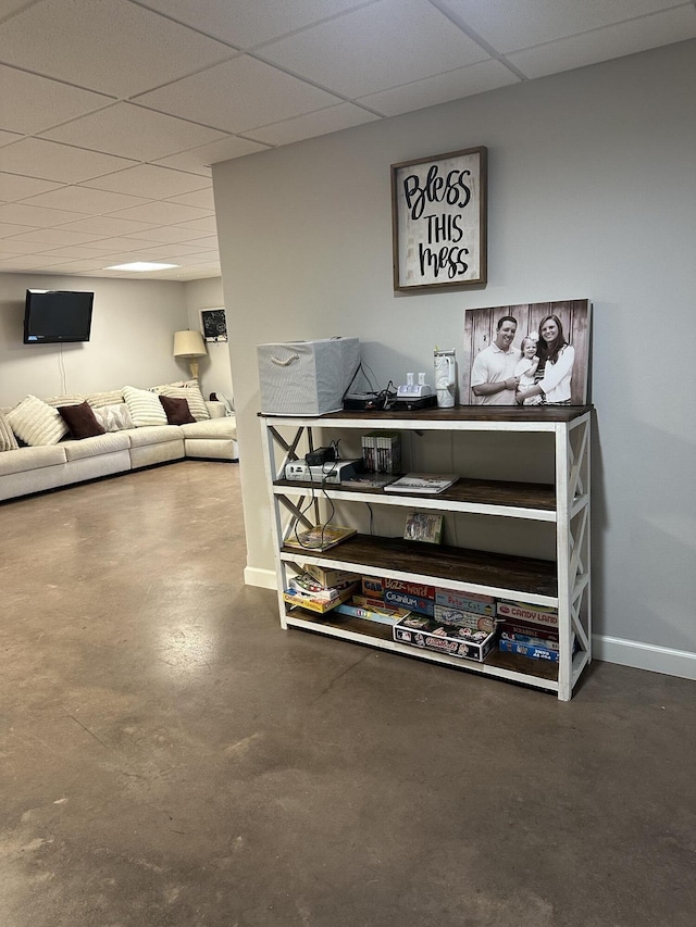 interior space with a paneled ceiling, baseboards, and finished concrete floors