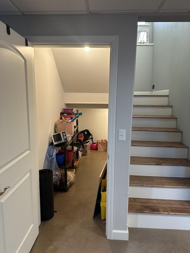 stairs featuring a drop ceiling and concrete floors