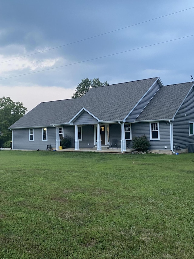 single story home with a porch, a shingled roof, and a front yard