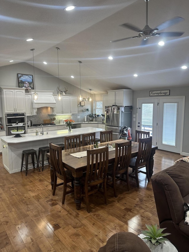 dining area with a ceiling fan, dark wood-style flooring, and vaulted ceiling