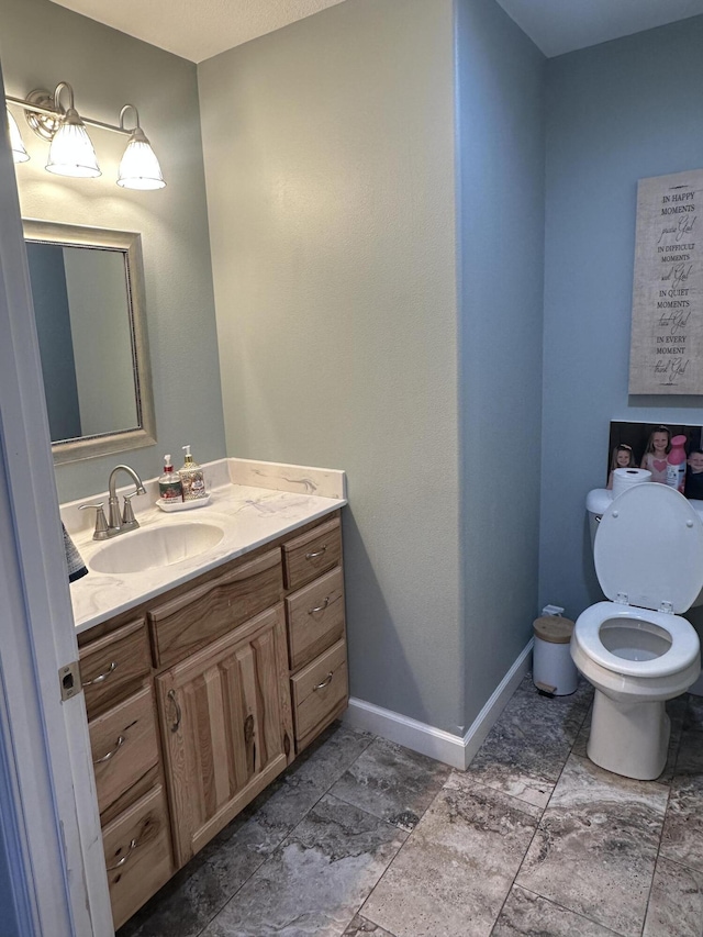 bathroom with toilet, vanity, and baseboards