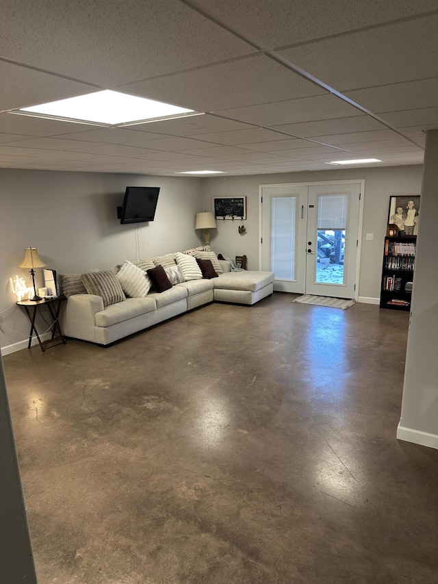 unfurnished living room featuring a paneled ceiling, baseboards, and concrete floors