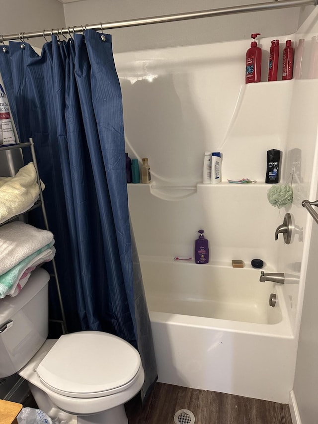 bathroom with toilet, shower / tub combo with curtain, and wood finished floors