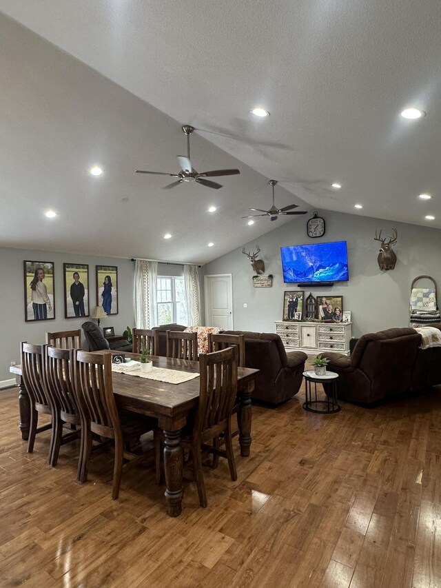 dining space with wood-type flooring, a textured ceiling, and lofted ceiling