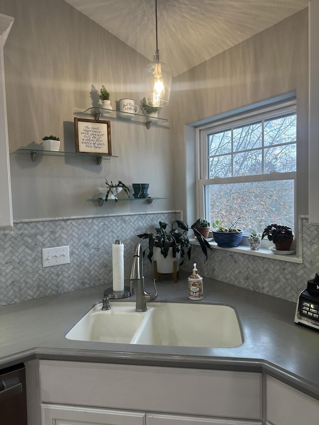 kitchen with a sink, tasteful backsplash, dishwasher, and white cabinetry