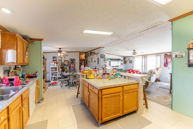 kitchen with a textured ceiling, light countertops, a center island, and ornamental molding