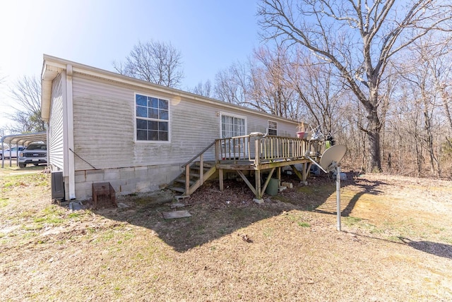 rear view of house with a detached carport, a deck, and dirt driveway