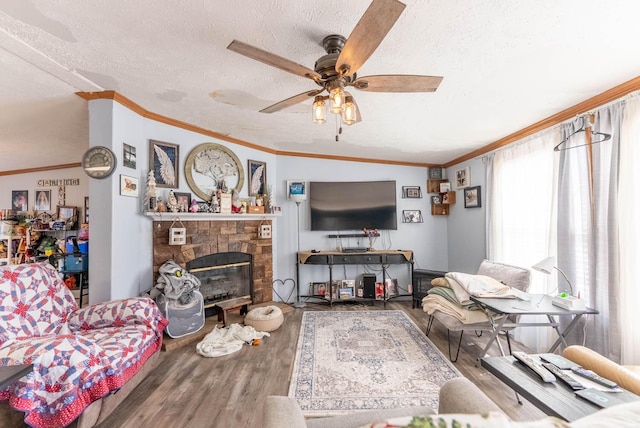 living area featuring a textured ceiling, wood finished floors, a fireplace, and ornamental molding