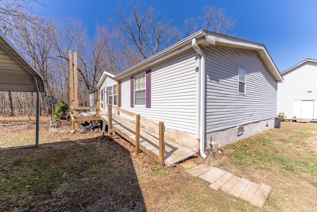 view of side of home featuring crawl space, a lawn, and a wooden deck