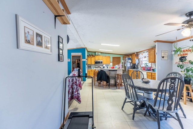 dining room featuring lofted ceiling, ornamental molding, light tile patterned floors, a textured ceiling, and a ceiling fan