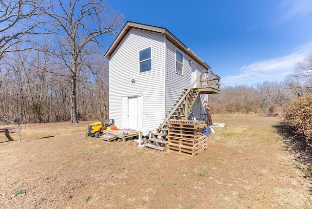 view of home's exterior with stairway, a lawn, and a wooden deck