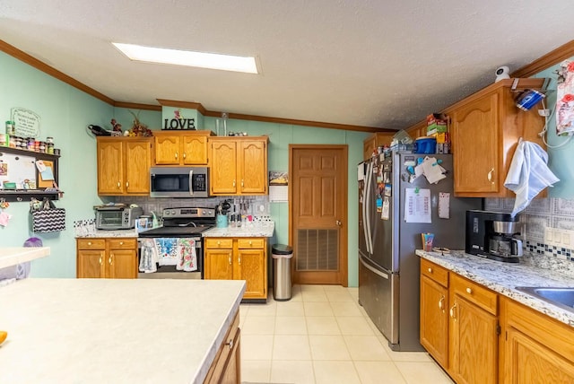 kitchen with crown molding, light countertops, decorative backsplash, brown cabinets, and stainless steel appliances