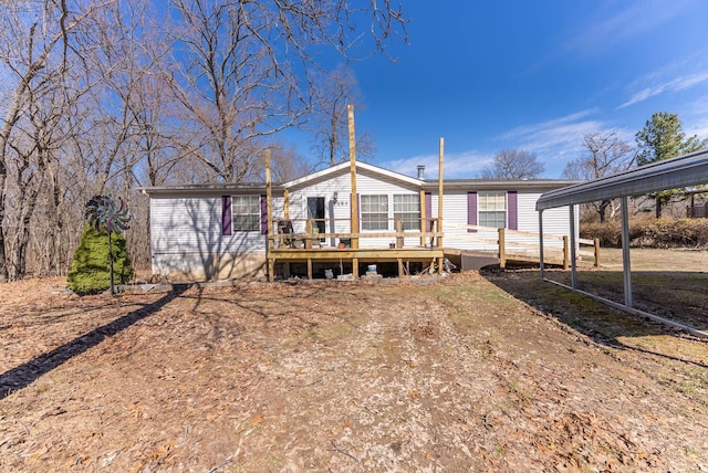 rear view of house featuring a wooden deck and a detached carport