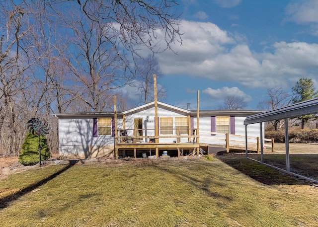 back of house with a detached carport, a yard, and a wooden deck