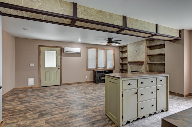 kitchen with dark wood-type flooring, baseboards, stainless steel counters, and a wall mounted air conditioner