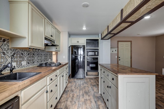 kitchen featuring black appliances, butcher block countertops, open shelves, under cabinet range hood, and a sink