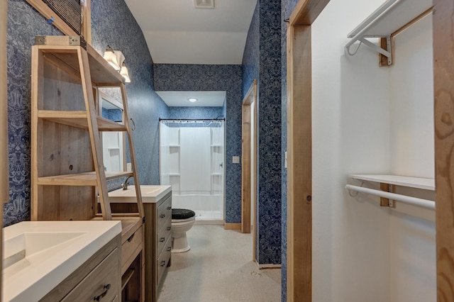 bathroom featuring toilet, two vanities, a sink, a shower stall, and wallpapered walls