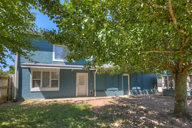 view of front of property featuring concrete block siding and fence