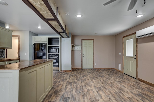 kitchen featuring wooden counters, baseboards, wood finished floors, black appliances, and a wall mounted AC