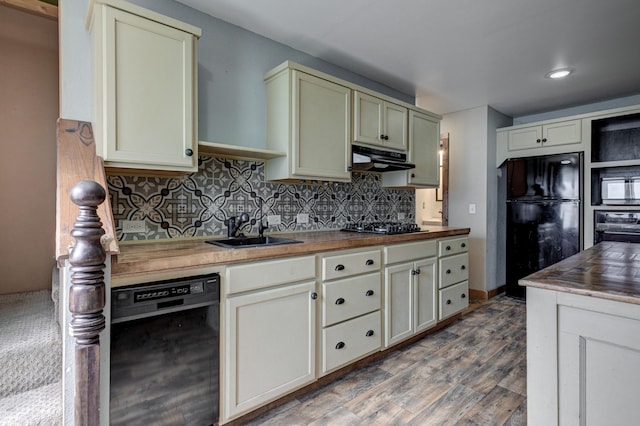 kitchen featuring under cabinet range hood, butcher block countertops, decorative backsplash, black appliances, and a sink