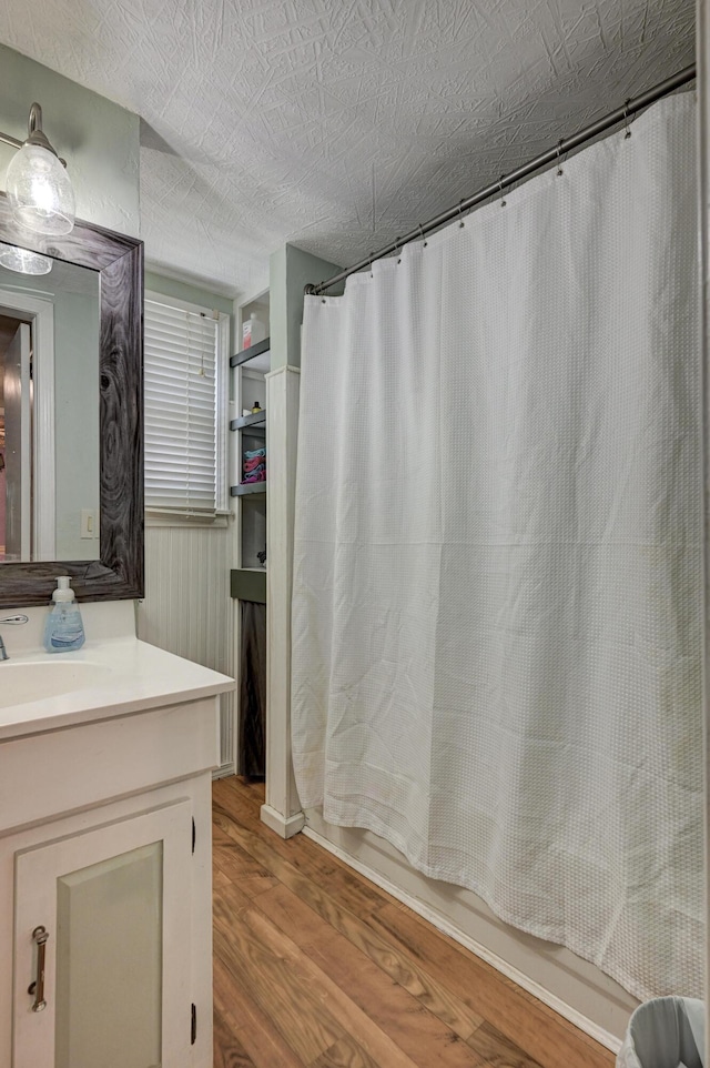 bathroom featuring a textured ceiling, vanity, shower / bath combo with shower curtain, and wood finished floors