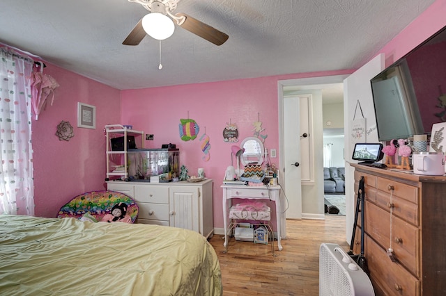 bedroom featuring baseboards, light wood-style floors, ceiling fan, and a textured ceiling