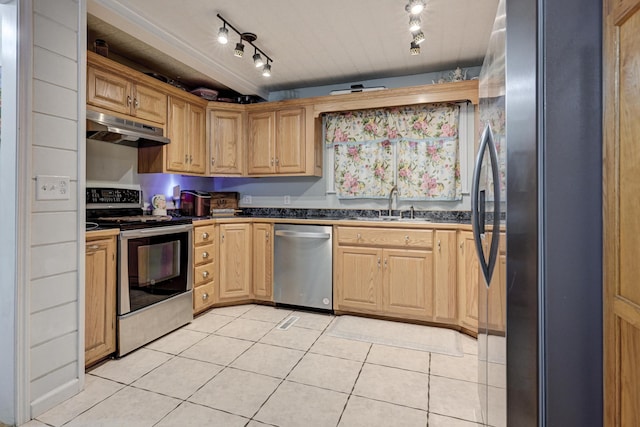 kitchen featuring light tile patterned flooring, a sink, stainless steel appliances, under cabinet range hood, and dark countertops