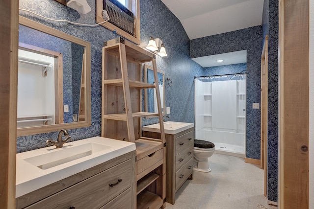 bathroom with wallpapered walls, a shower stall, two vanities, and a sink