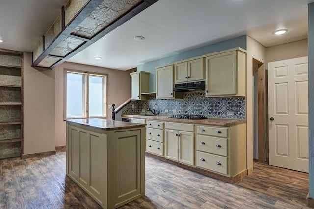 kitchen with under cabinet range hood, cream cabinetry, dark wood-style flooring, and butcher block counters